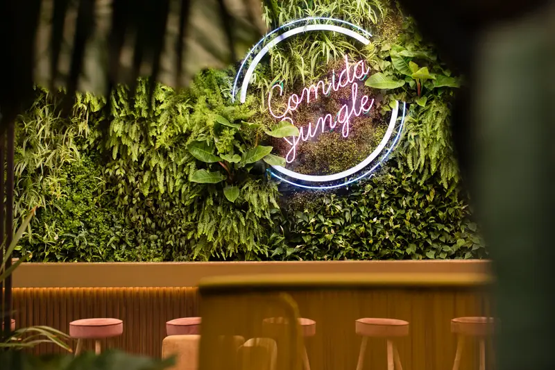 L’insegna al neon Comida Jungle sul muro verde
